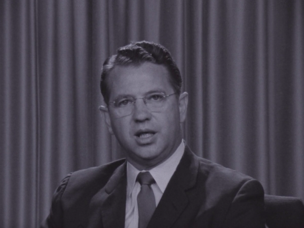 picture of senator Hartke in a suit and tie against curtained background