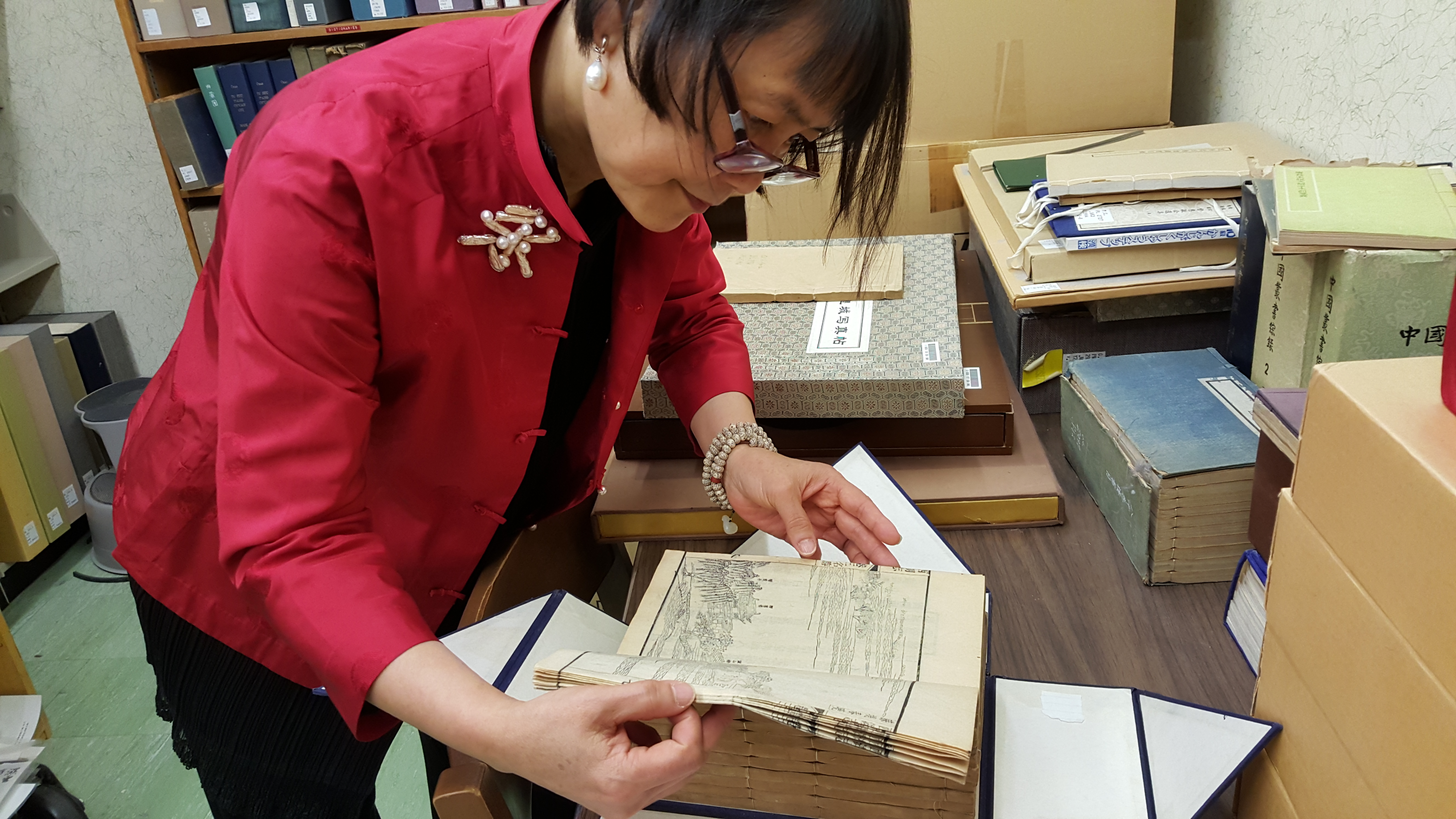 Color photograph of a researcher looking at a book from the East Asian Collection.