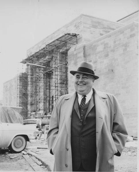 Photograph of Herman B Wells with a building under construction in the background