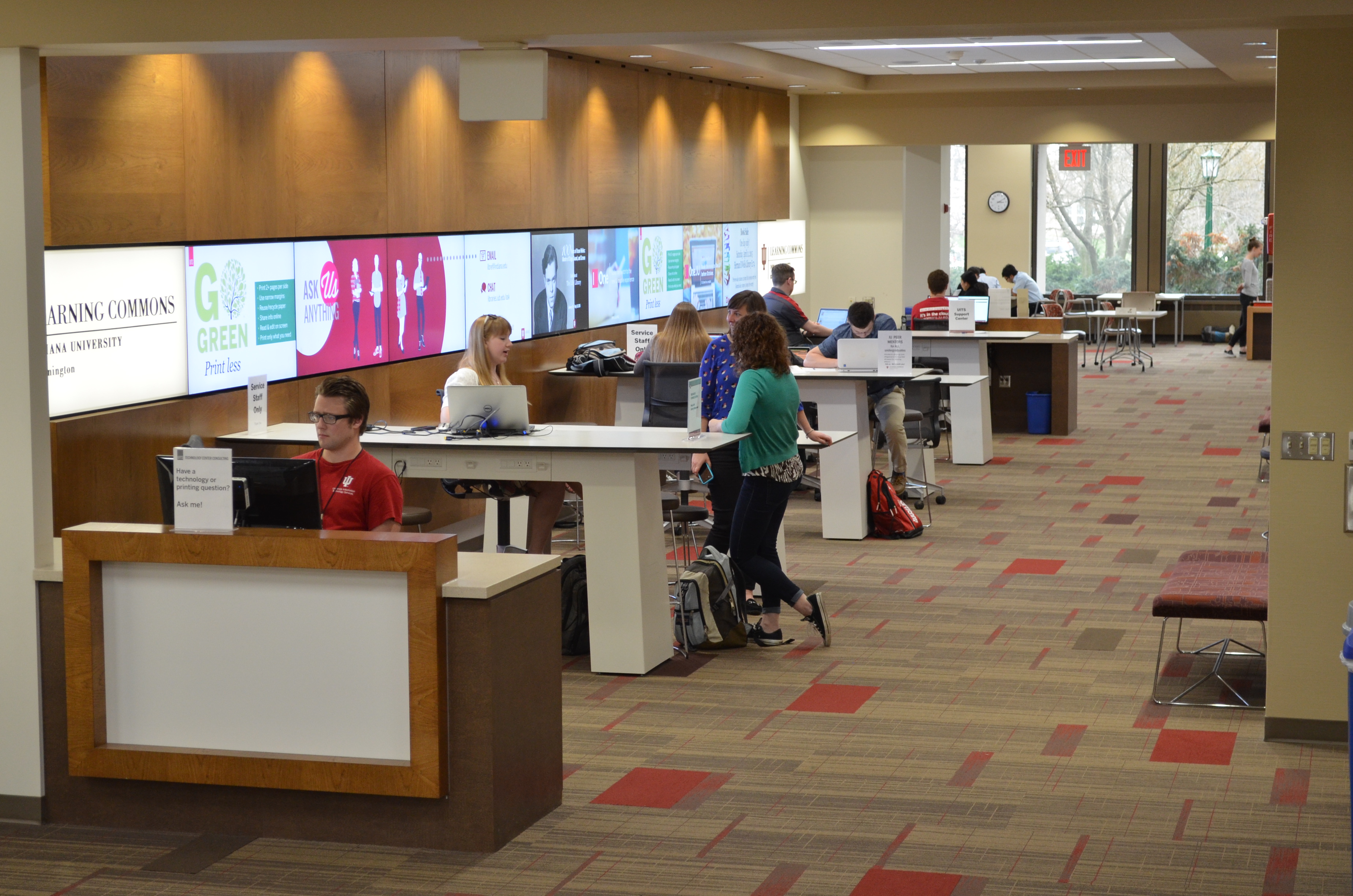  Color photograph of students working at tables in the Wells Library Learning Commons.