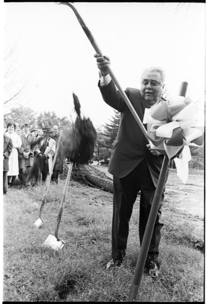 Black and white photograph of Herman Wells shoveling dirt during a groundbreaking ceremony.