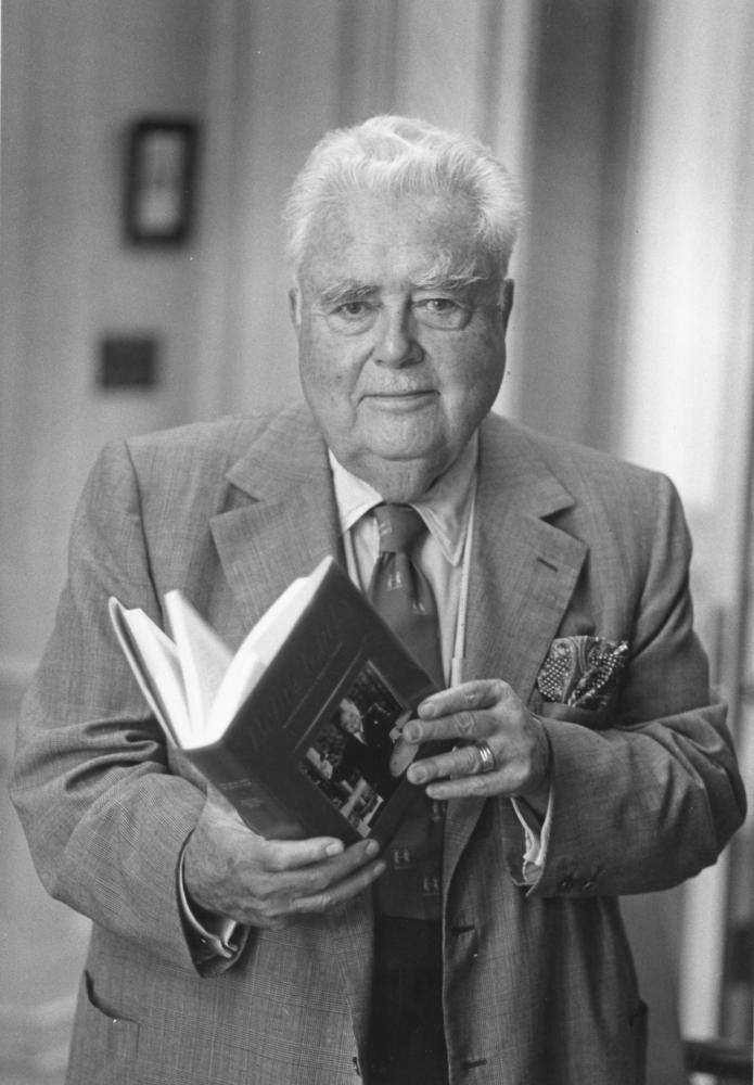 Wells holding copy of his autobiography Being Lucky, 1980