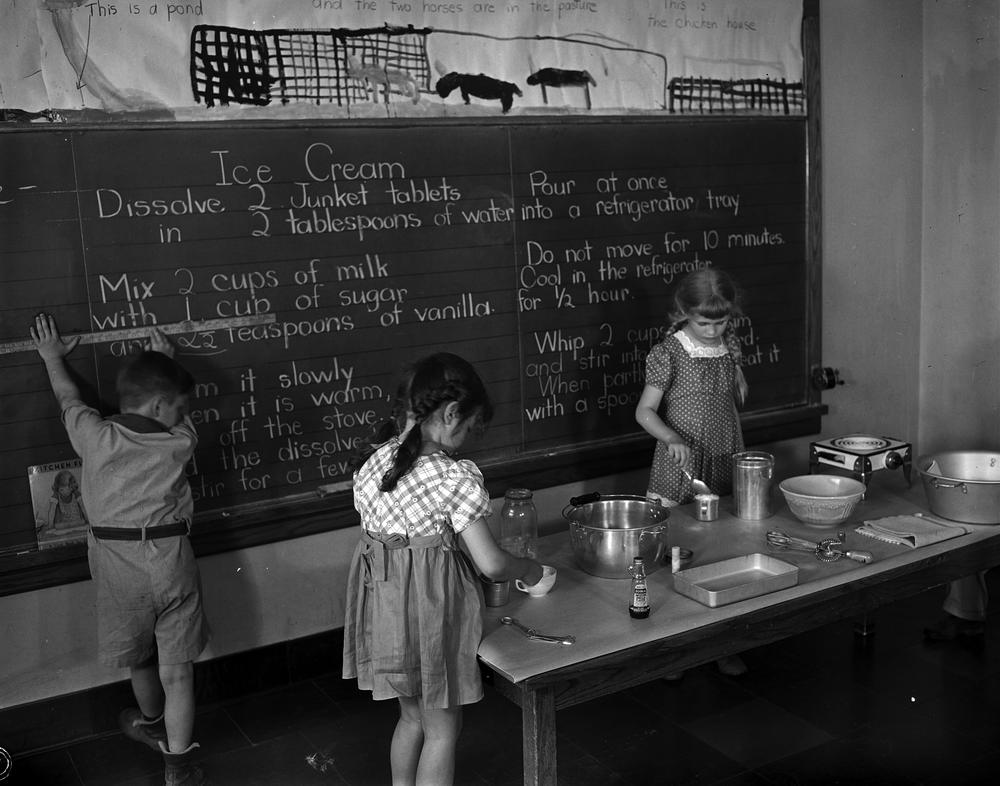 Photograph of three children making ice cream in a classroom