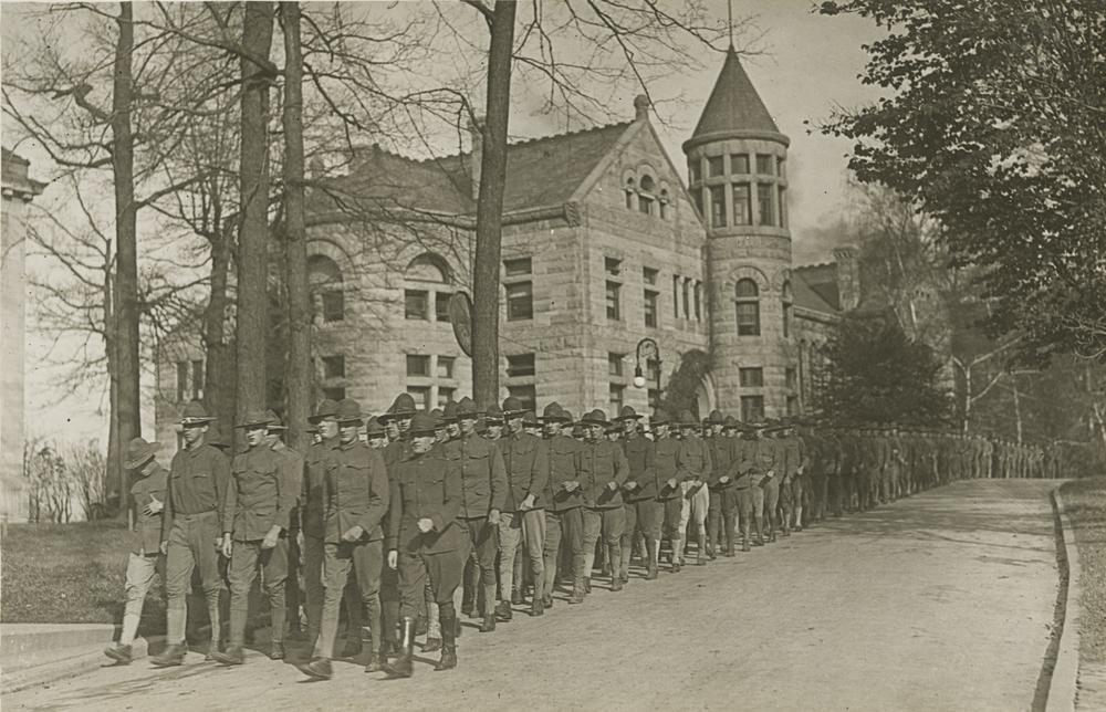Photograph of soldiers in uniform parading past Maxwell Hall