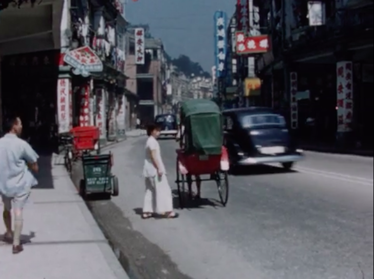 street scene in singapore showing a woman in all white in the street next to a carriage