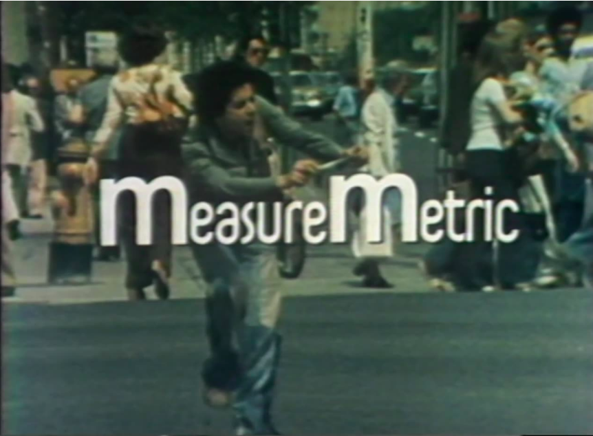 Title screen for Measure metric, shows the title in white font with an image of a man on a city street walking around with a measuring tape