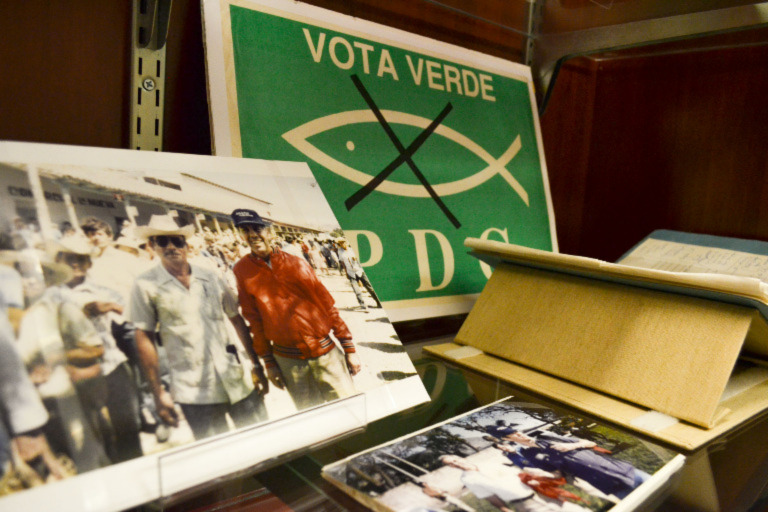 Various items in an Archives display case, including photographs and a placard reading "Vota Verde."