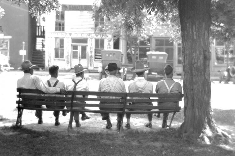 Six men sitting on a park bench, viewed from behind, photograph known as "Liar's Bench."