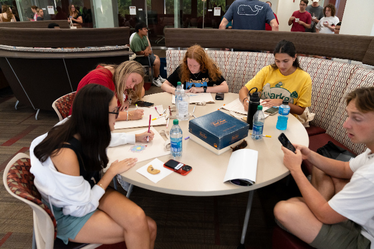 Students seated around a table playing Trivial Pursuit