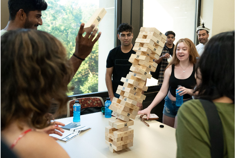Students look in in surprise as a Jenga tower topples.