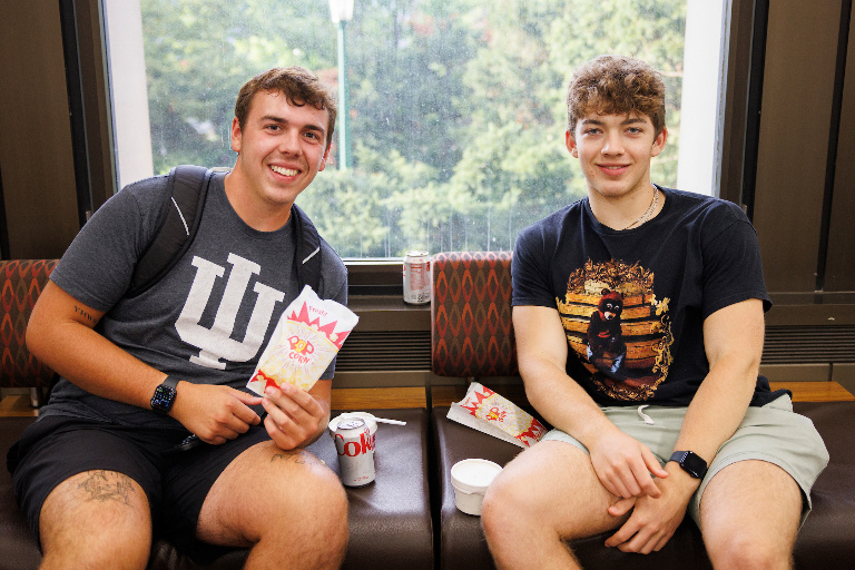 Two smiling students with bags of popcorn.