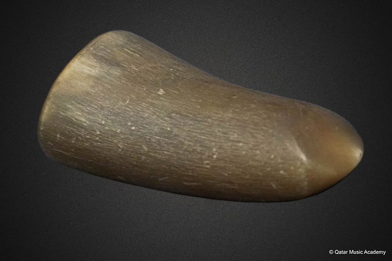Close-up view of a piece of brown cow horn which is used to pluck instrument strings.
