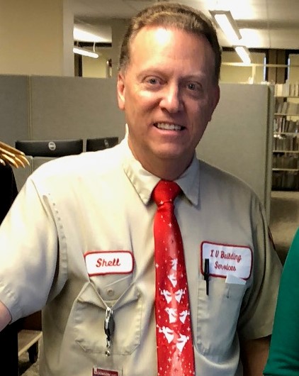 Man smiling with red Holiday tie in his Facility Operations uniform.