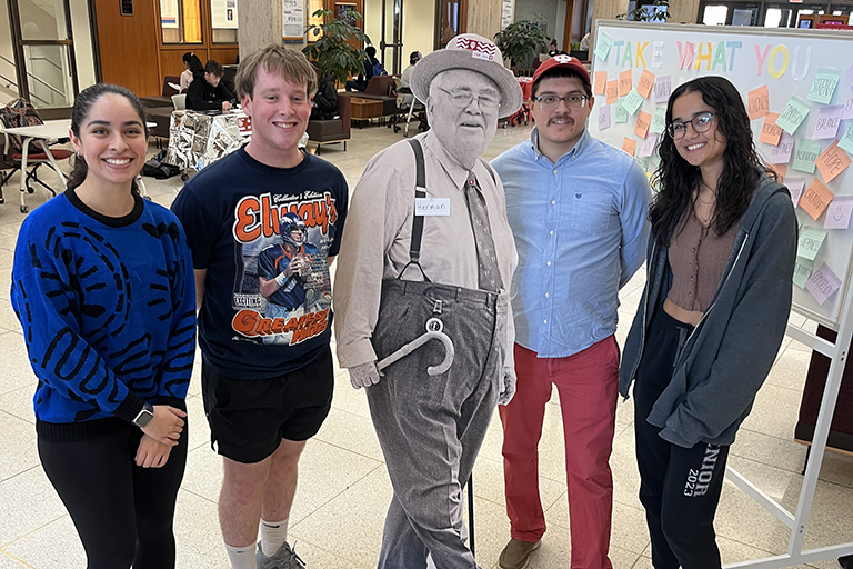 Four young people stand posed next to a cardboard cut-out of a life-size Herman B Wells photo