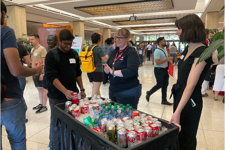 Library staff members stand behind a large cooler of bottled beverages while students help themselves.