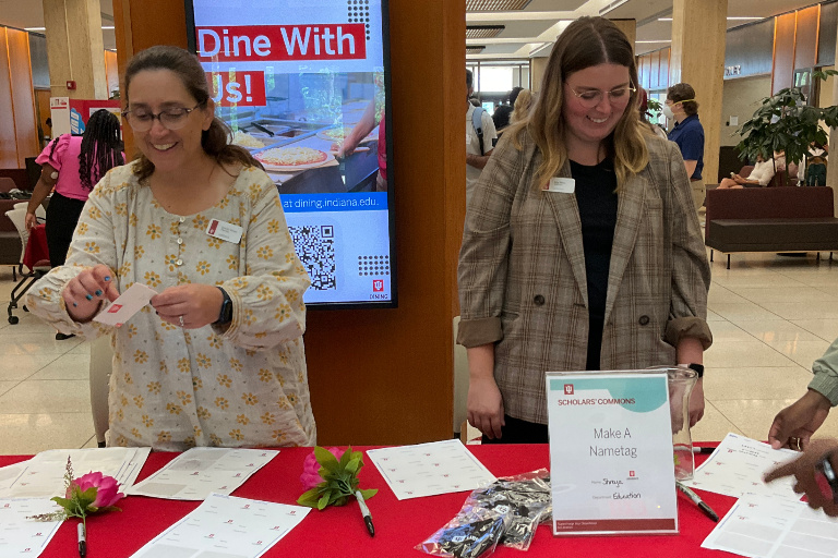 Two smiling librarians staff the "Make a Nametag" table.