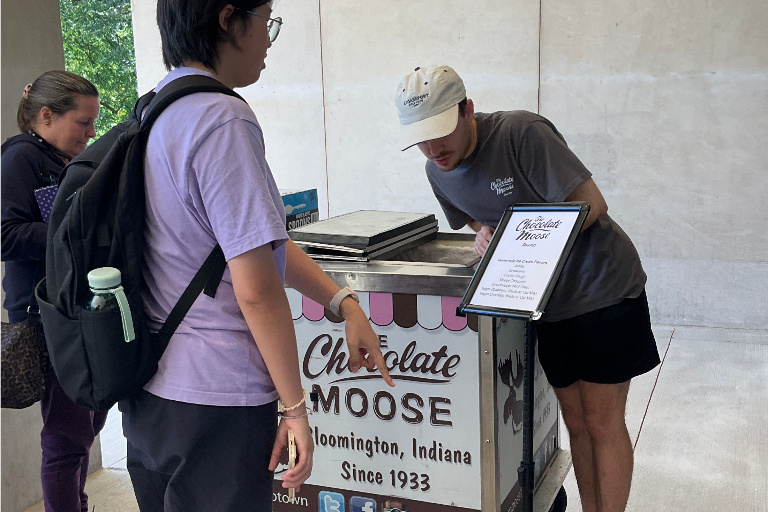 A Chocolate Moose employee serves cups of ice cream from a cart on the library patio.