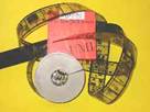 on a yellow background, a tan reel of microfilm with some of it spooled out, and a red microfilm box.