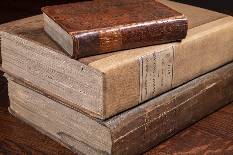 Three rare books are depicted on top of one another.