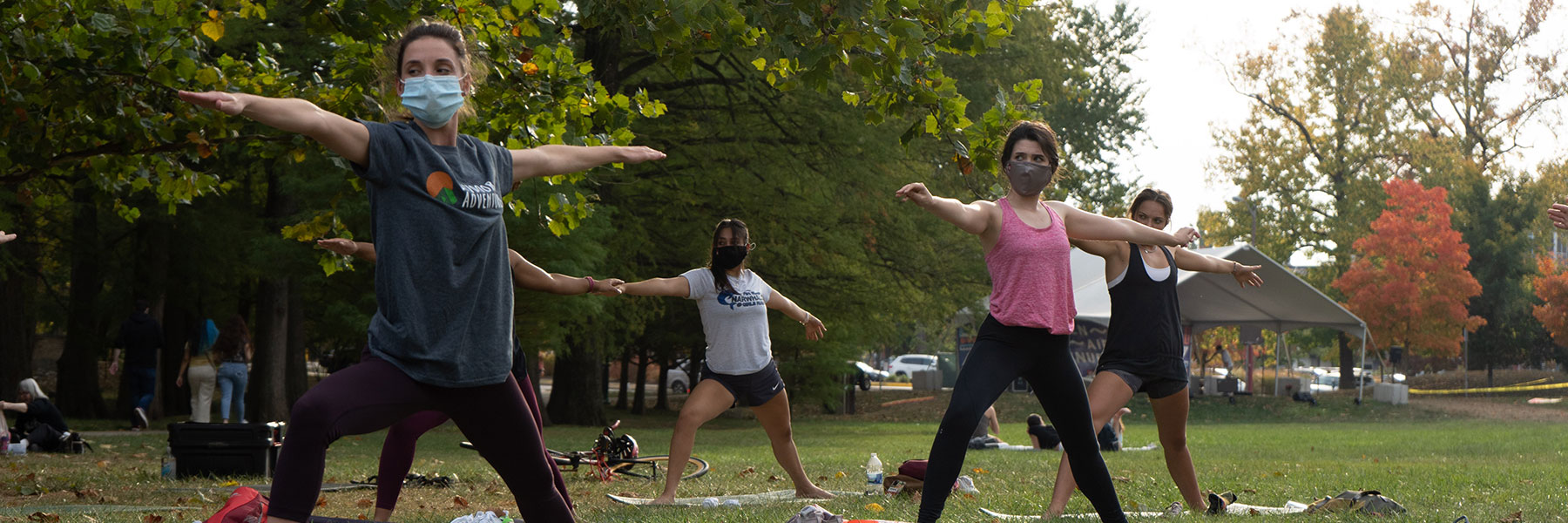 A group of students wearing face masks practice yoga outside on the IU Bloomington campus.