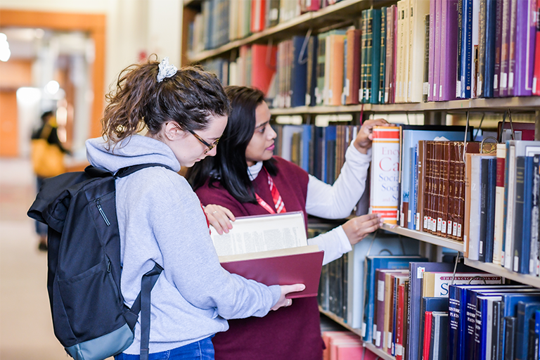 Two students look at books in the Reference Reading Room.