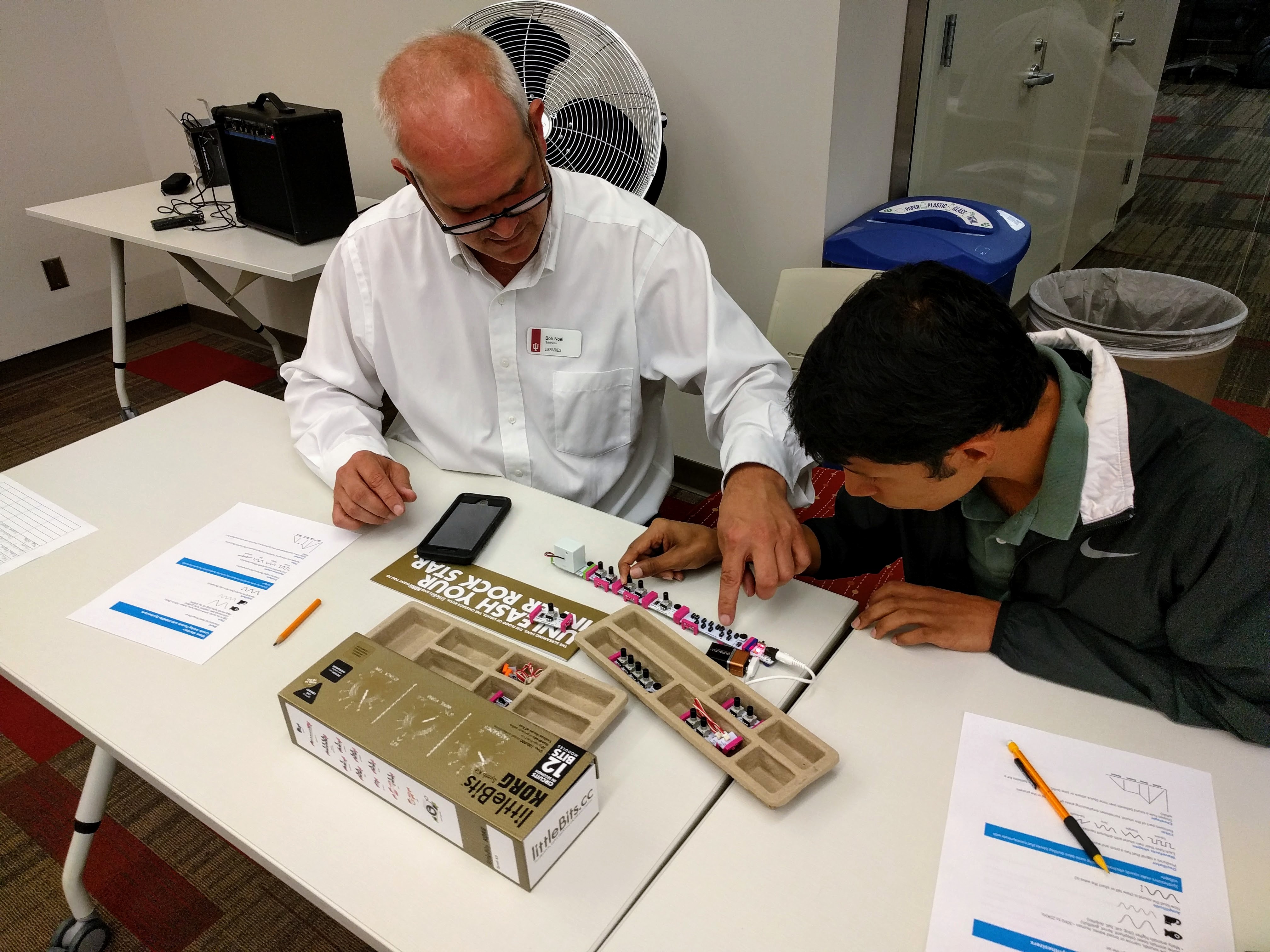 A student and librarian play with littleBits synthesizer kits.