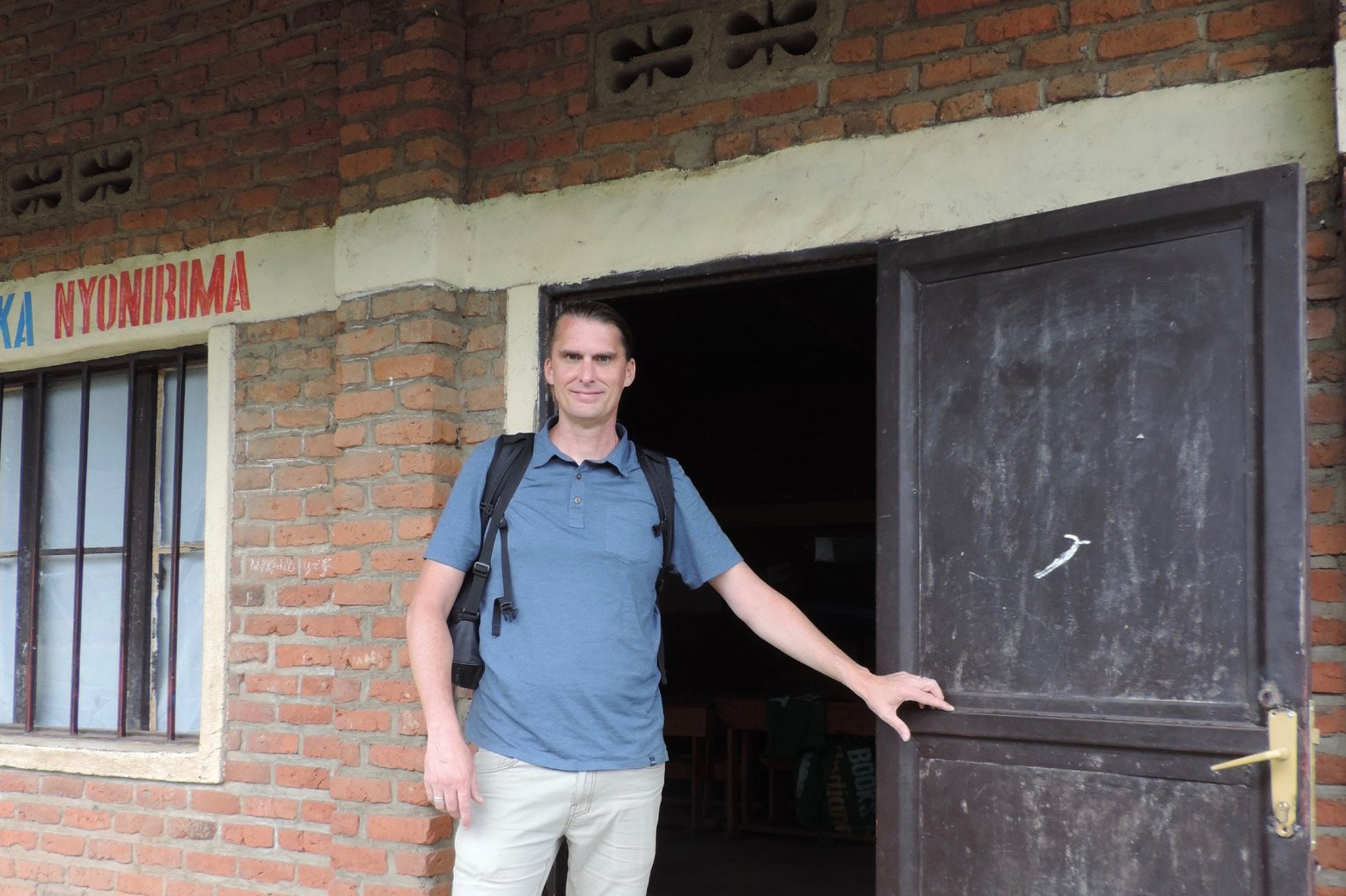 Photo of Mike Courtney, Outreach and Engagement Librarian, in front of a door in Rwanda.