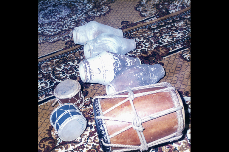 Seven drums of three types lie on an oriental rug.
