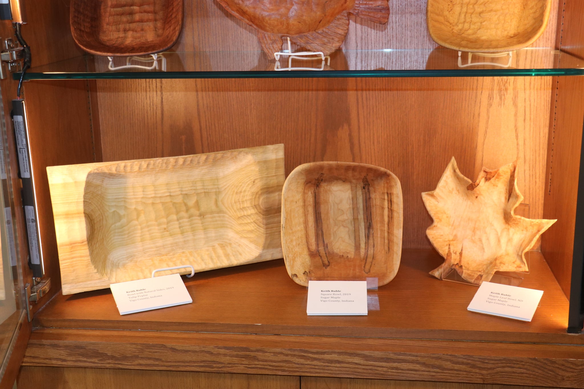 Three wooden bowls on display. One is shaped like a maple leaf.