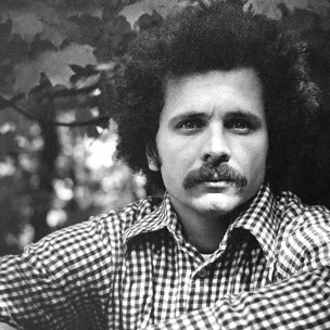 Frank Lester, with curly hair, a thick mustache, and wearing a checkered collared shirt. Photo dates to 1970s.