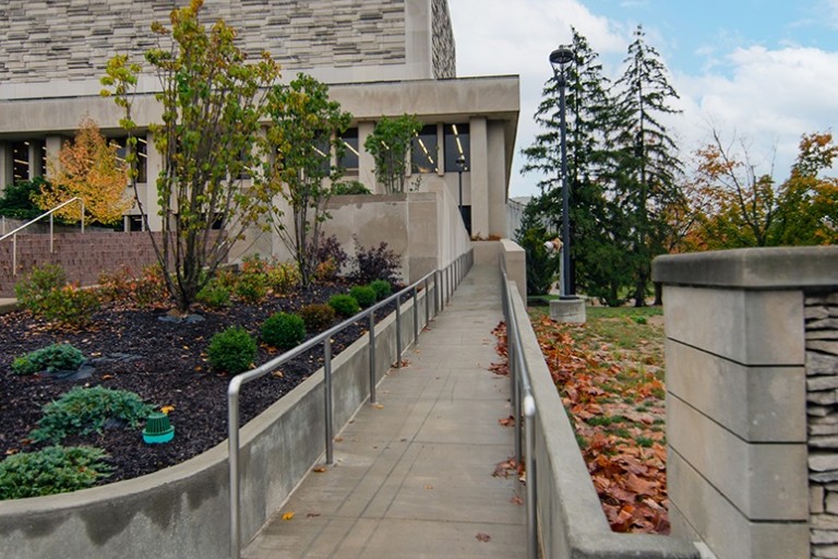 A long, concrete ramp with a silver railing slopes up to the Herman B. Wells Library.