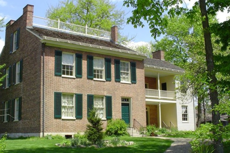 A two-story brick house with green shutters and door.