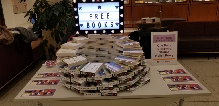A sign advertising free books sits upon a circle of books stacked like bricks.