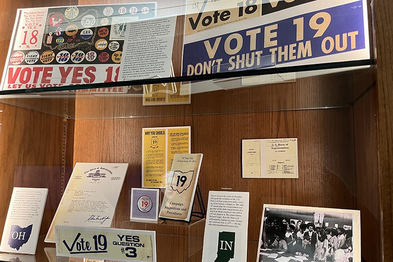 Display case filled with vintage right-to-vote posters and documents.