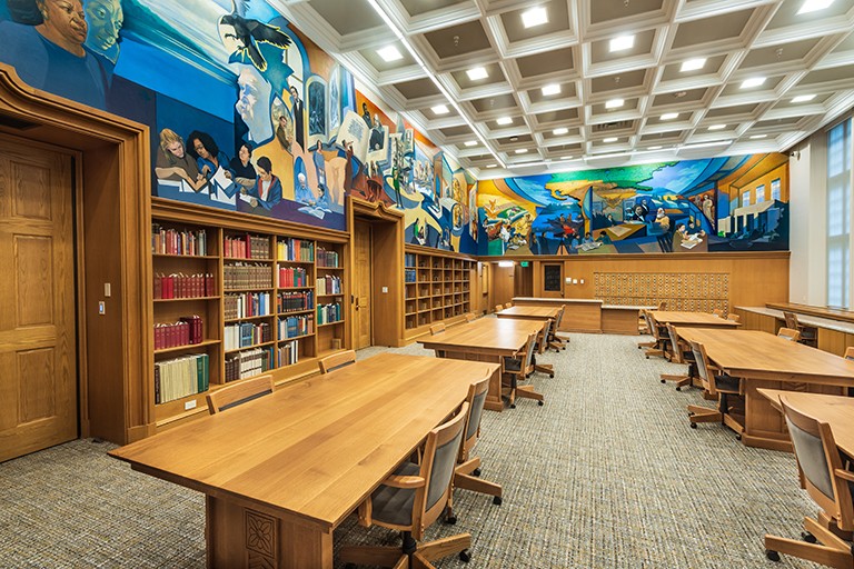 The interior of the Lilly Library Reading Room is empty and two walls of its murals are shown