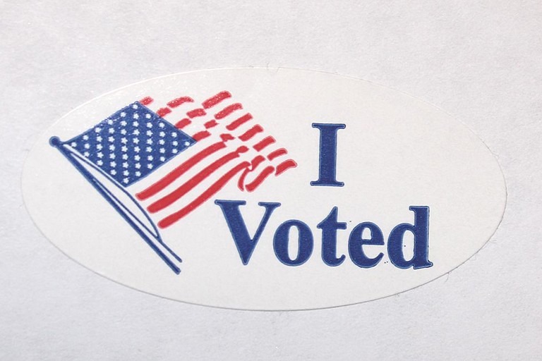 An "I voted" sticker also bearing a waving American flag.