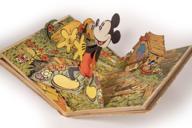 A photo of a pop-up book page featuring Mickey Mouse emerging from the spread with his dog Pluto behind him.