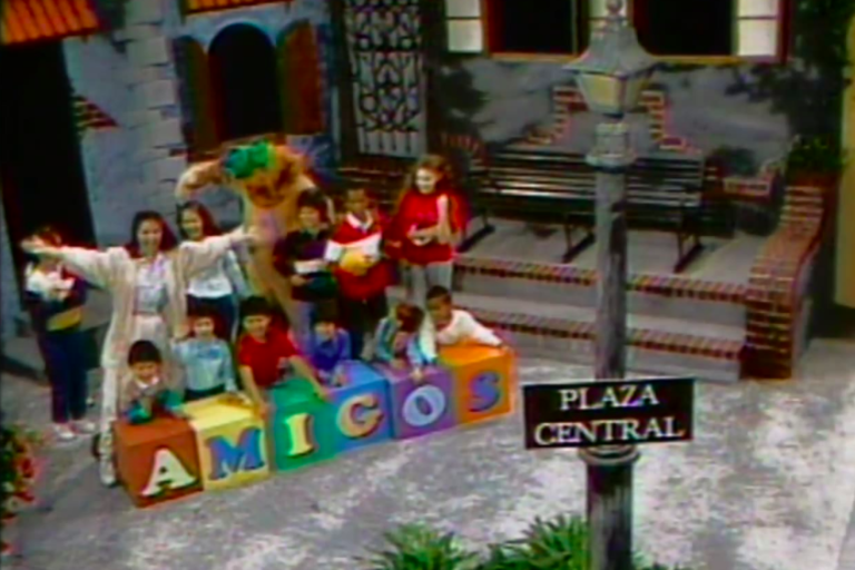 title card for Amigos showing kids and the show's hosts gathered around blocks on a street corner stage