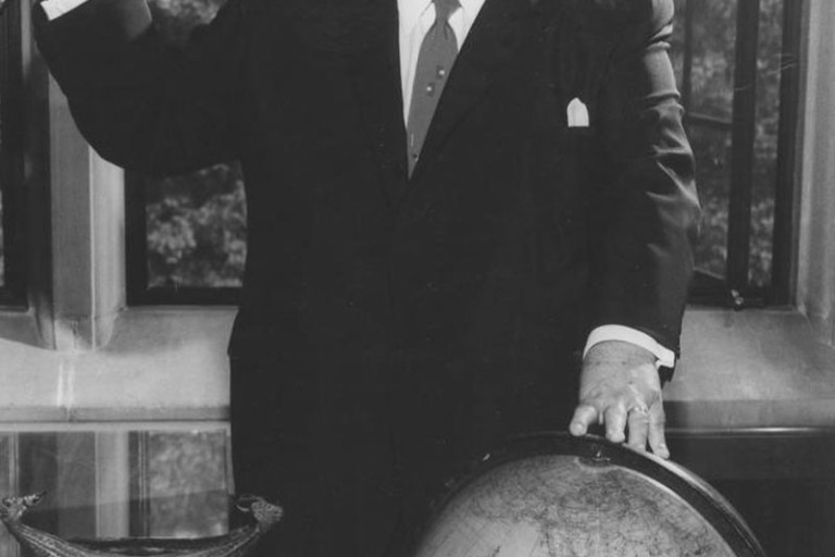  Herman B Wells with Globe and ringing a bell in his office on September 6, 1961.