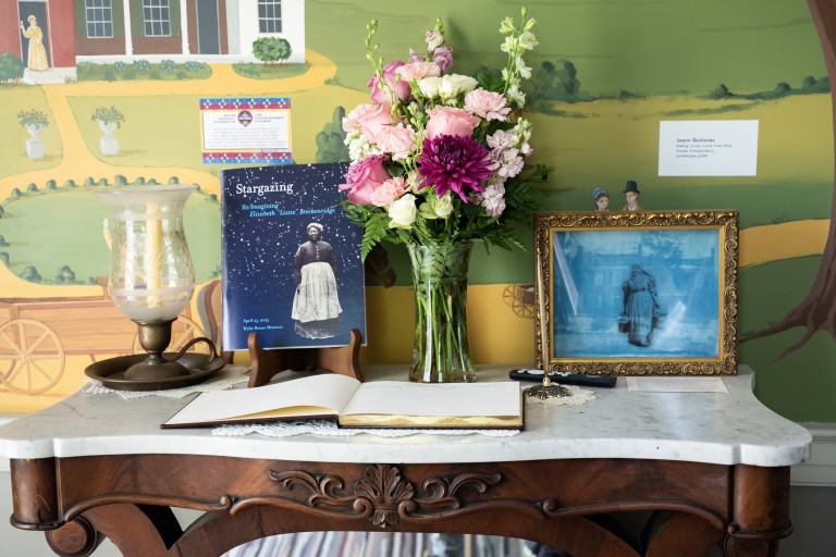 Entry table with flowers, framed image of Black woman, and event program