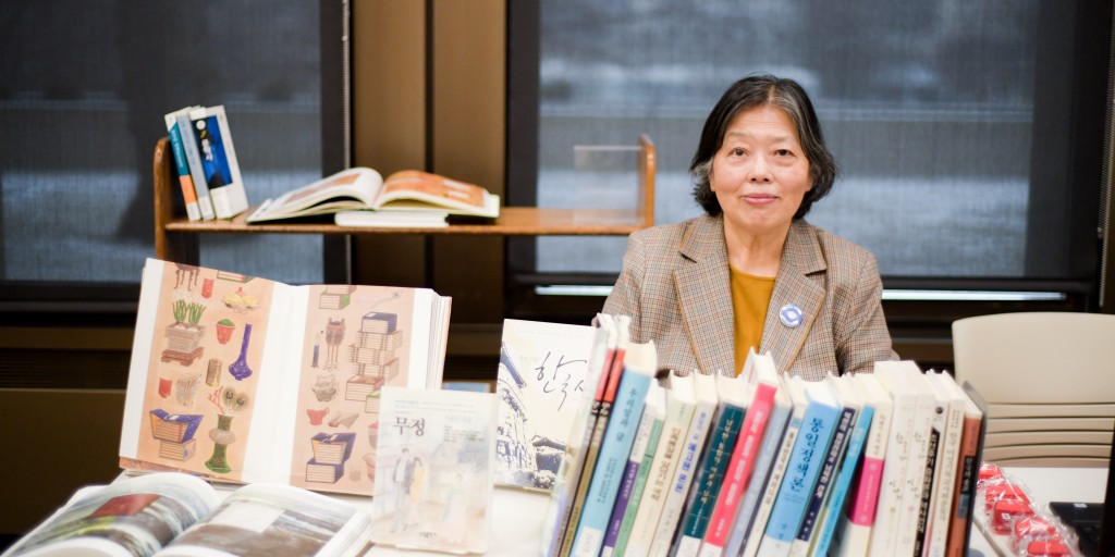 Tawianese woman in yellow shirt and plaid jacket behind collection of East Asain books.
