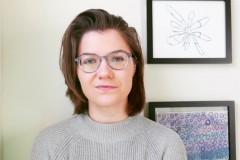 A women wearing glasses looks directly into the camera.